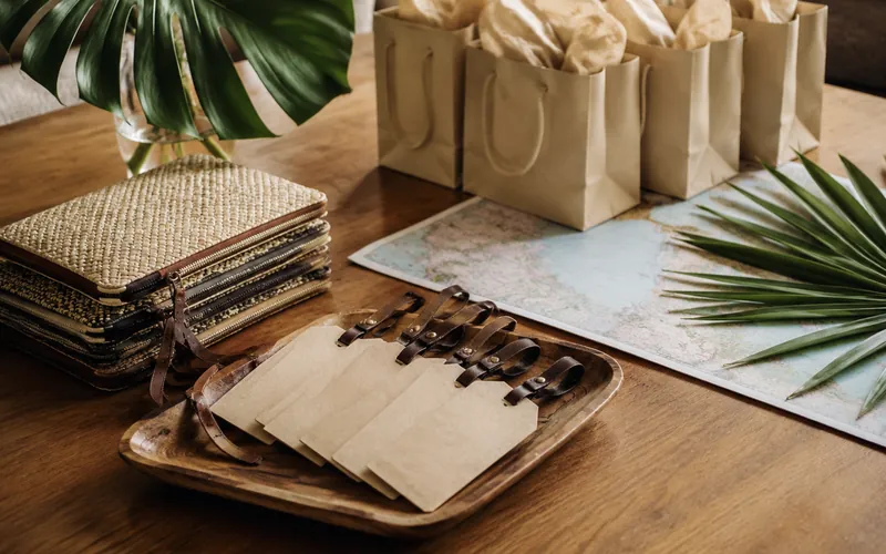 A wooden table set with blank welcome bags, luggage tags, folded pouches and an open map, ready to be handed out to arriving travelers.